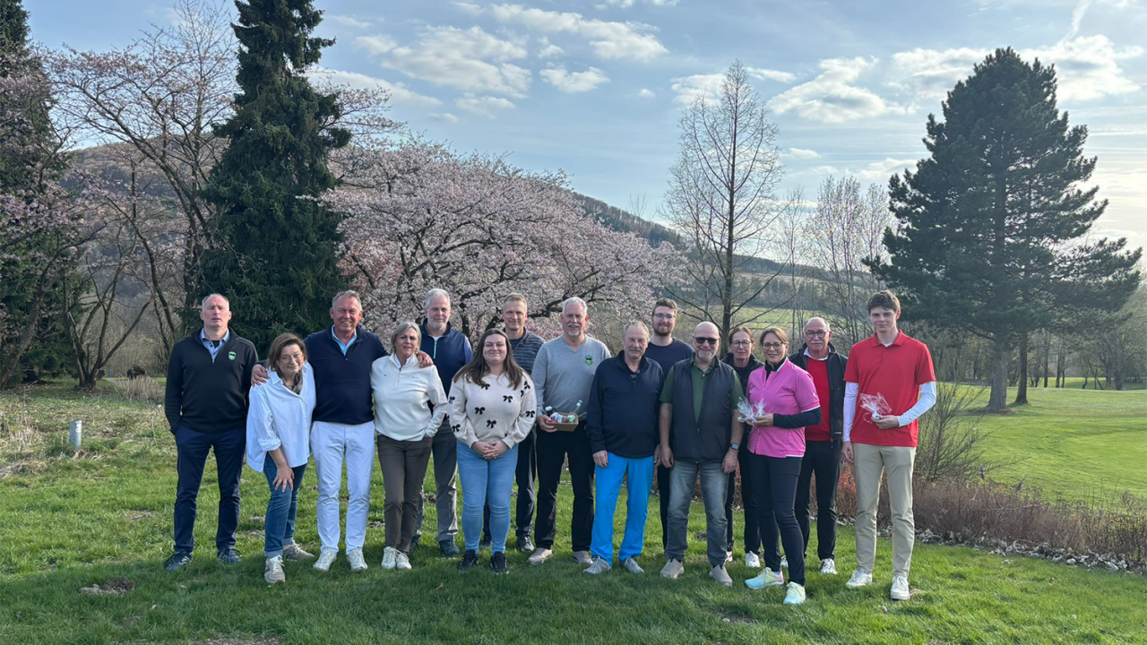 Eine Gruppe Golfer bei der Siegerehrung, im Hintergrund Bäume und ein Berg im Sauerland bei blauem Himmel