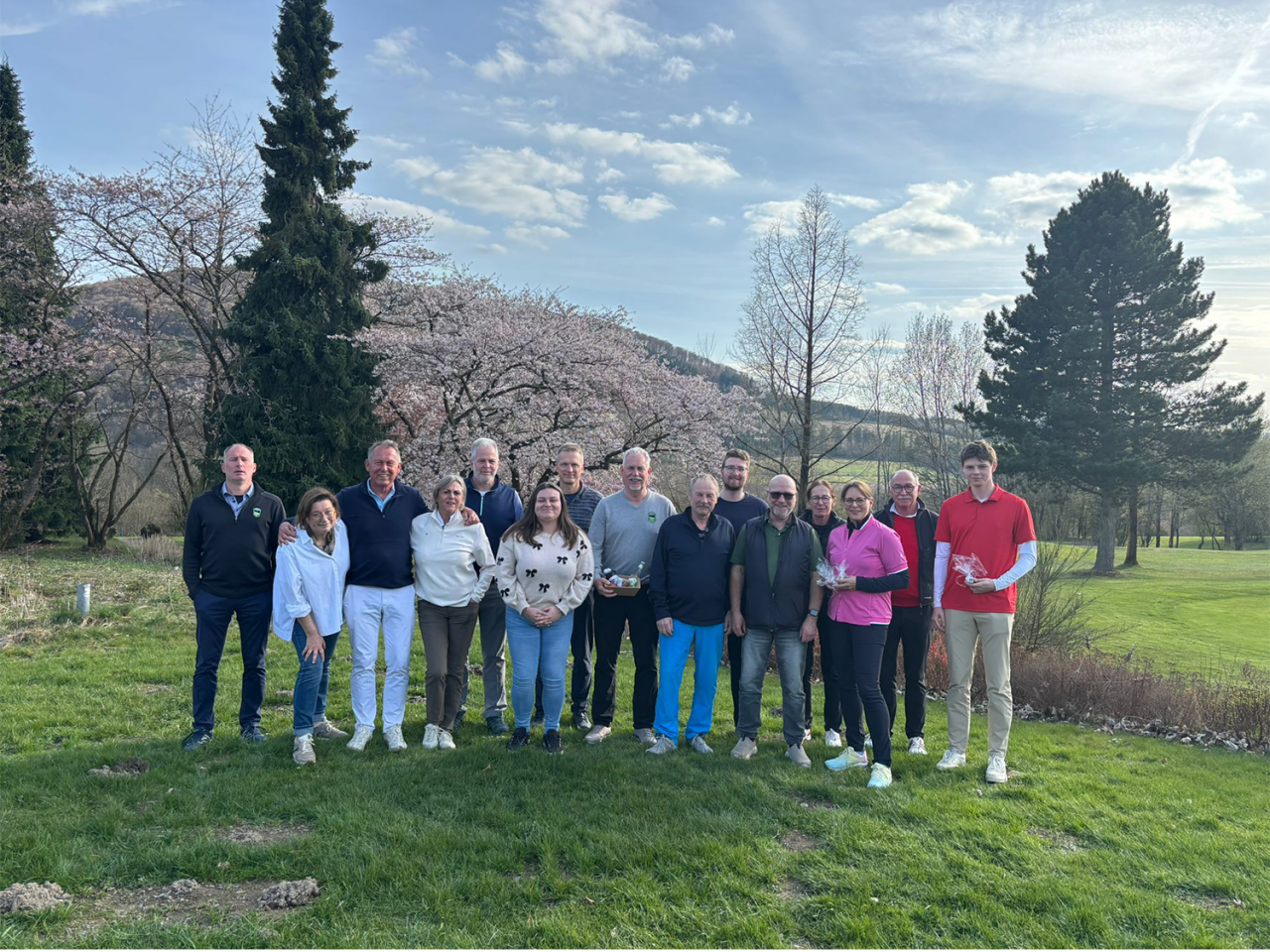 Eine Gruppe Golfer bei der Siegerehrung, im Hintergrund Bäume und ein Berg im Sauerland bei blauem Himmel