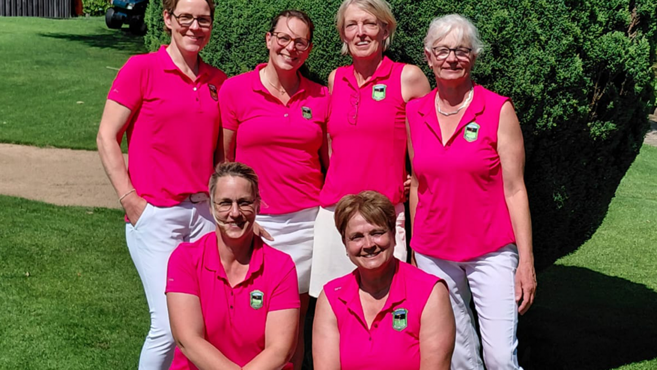 Damen AK50 GC Gimborner Land Die sechs Damen der AK50 des Golfclub Schmallenberg in Violetten Shirts und weißen Hosen vor einem grünen Busch bei blauem Himmel