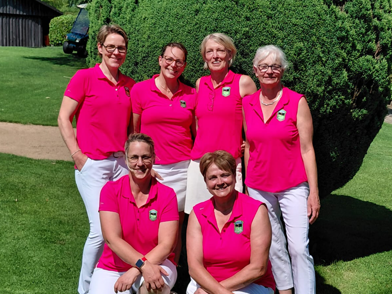 Damen AK50 GC Gimborner Land Die sechs Damen der AK50 des Golfclub Schmallenberg in Violetten Shirts und weißen Hosen vor einem grünen Busch bei blauem Himmel